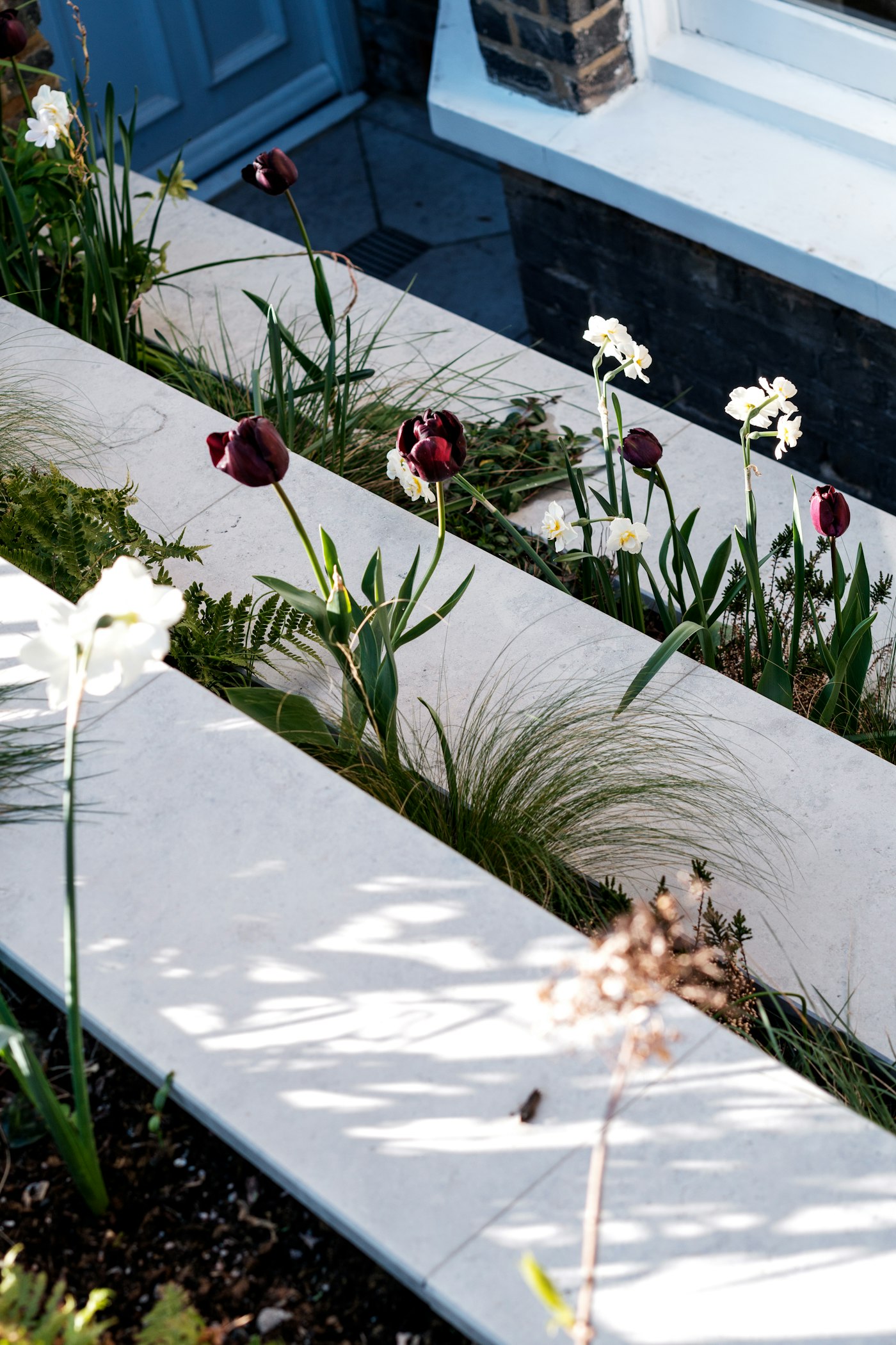 Lichte tegels met een strook bloeiende beplanting