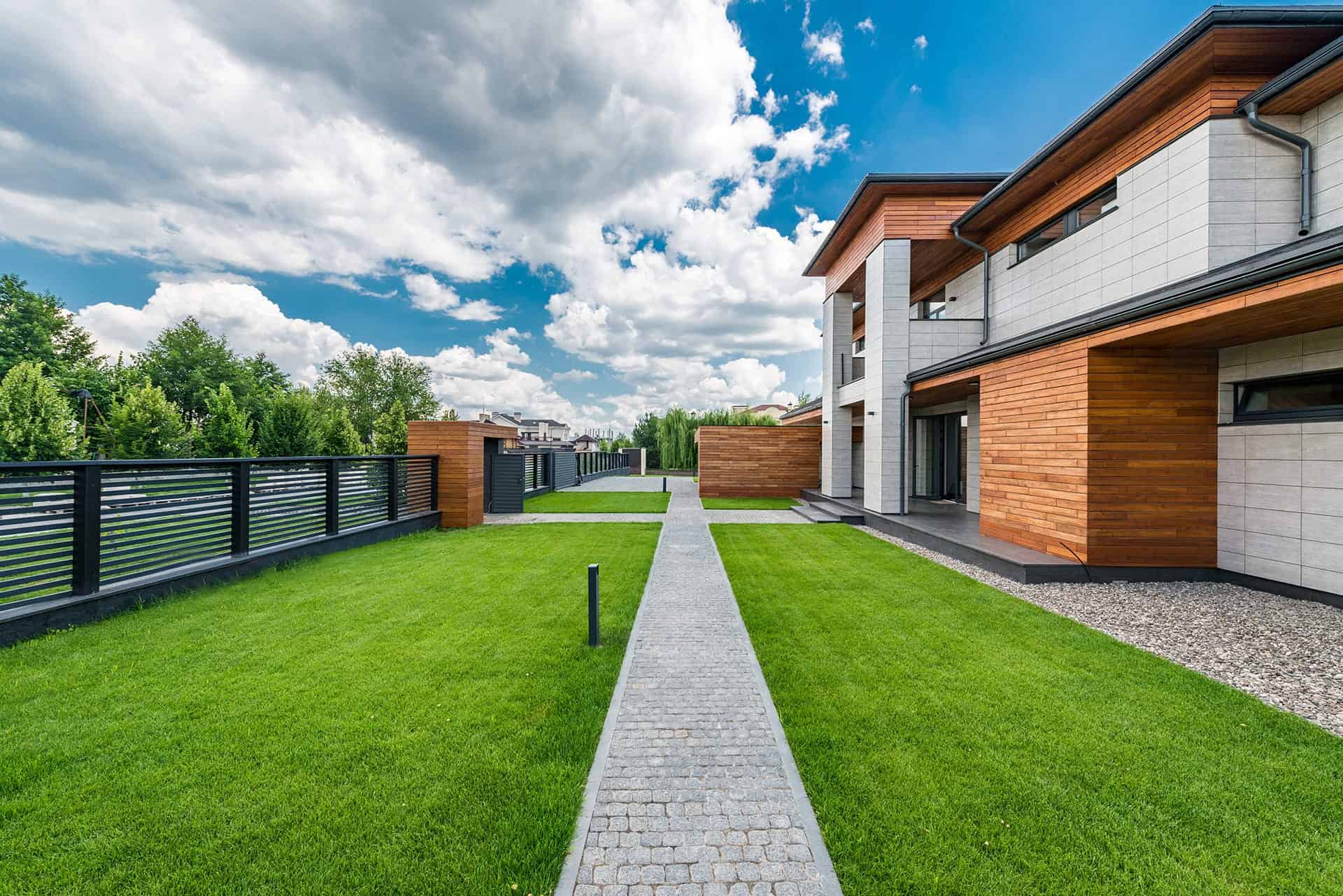 Bestraat tuinpad tussen twee gazons bij moderne woningen